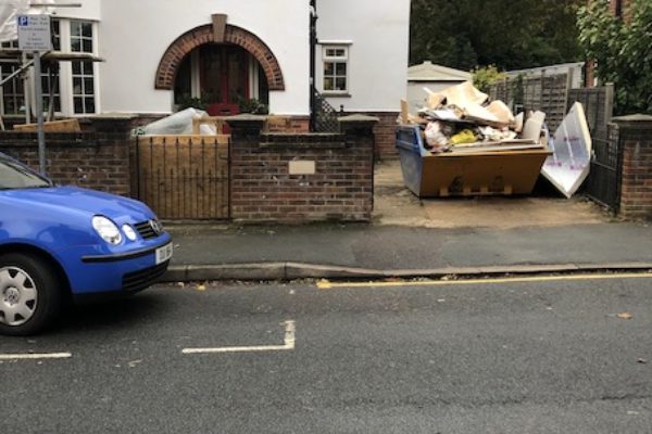 Overfilled skip on customers drive in Stoke Gifford